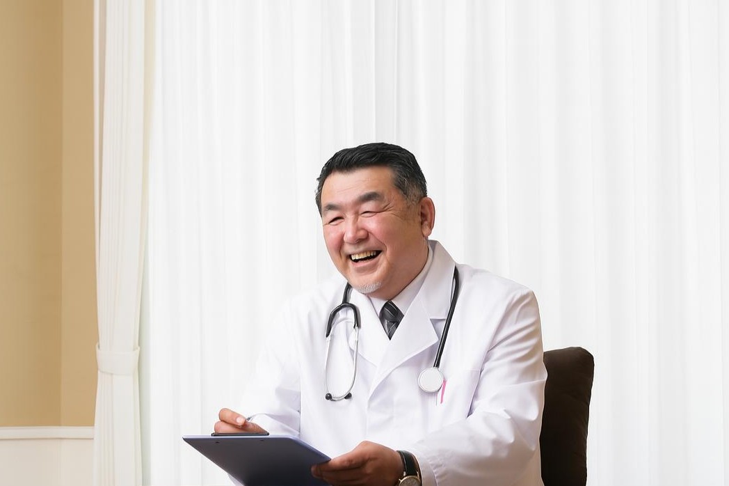 聴診器を首に掛けた白衣を着た笑顔の男性